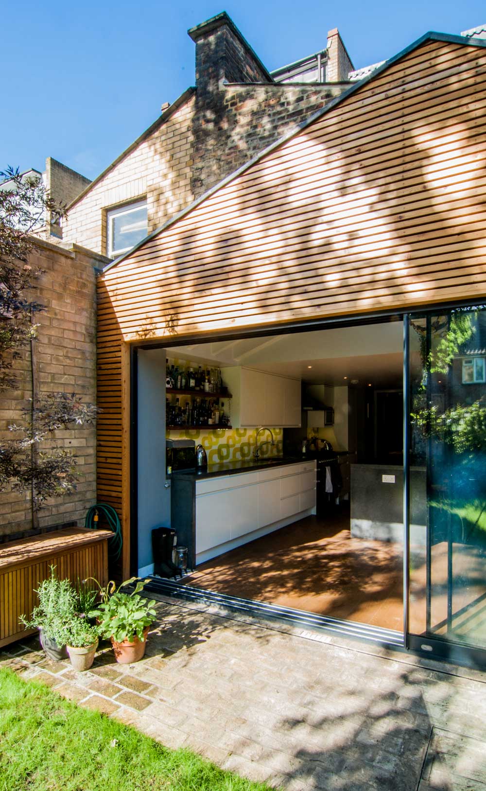 Timber cladding rear extension including large sliding doors overlooking the garden.