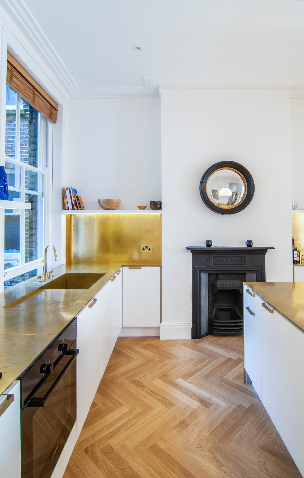 Beautiful brass gold worktops work perfectly with the parquet floors, white cabinets and black fireplace.