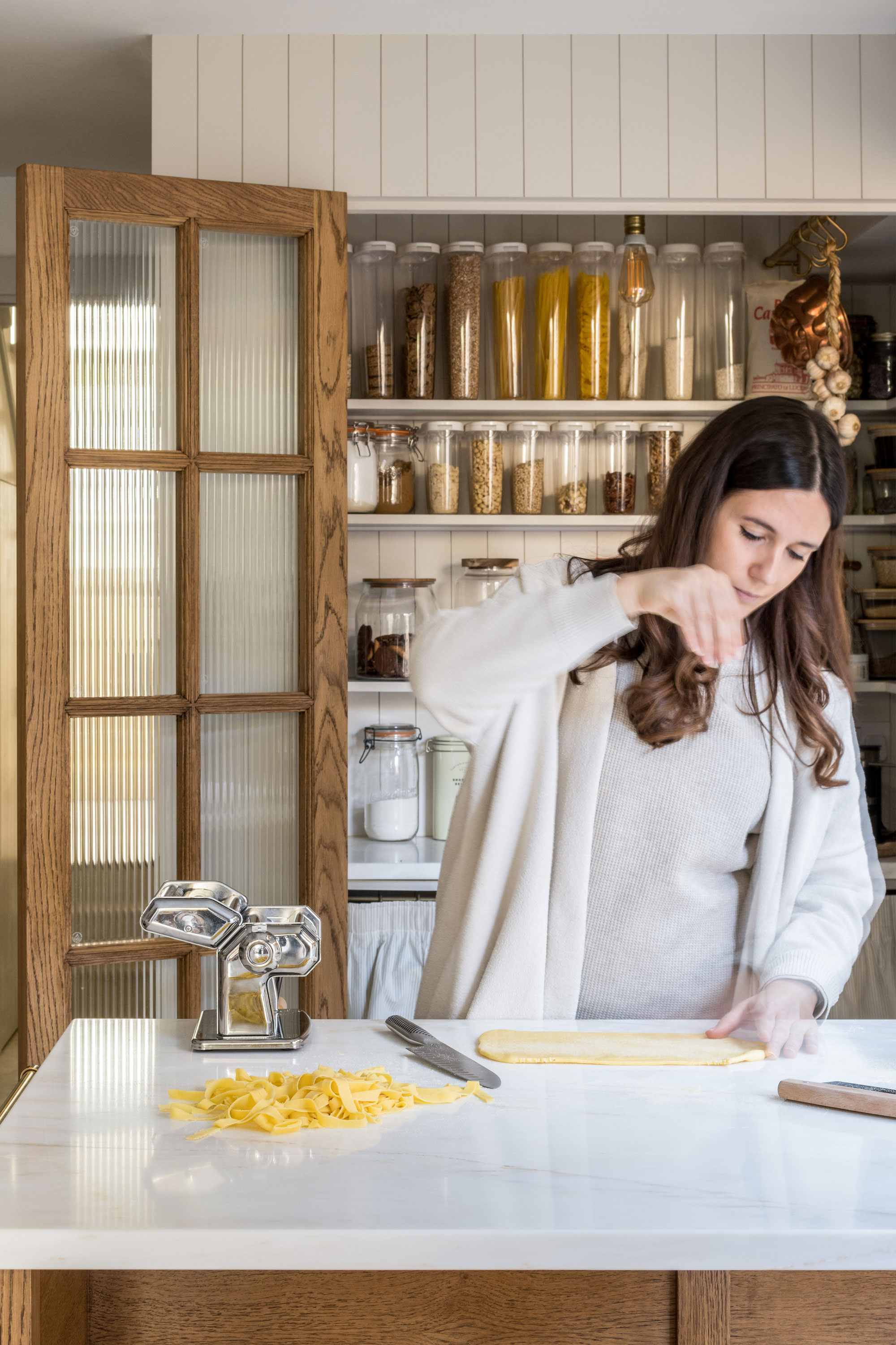 Martina cooking pasta on her rustic kitchen island with open joinery storage in the background