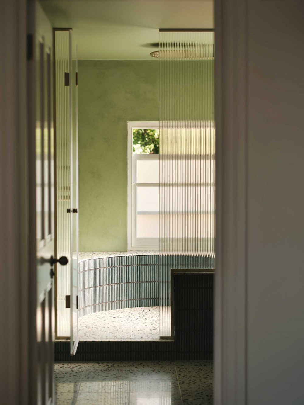 A curved shower with terrazzo tiles and fluted glass