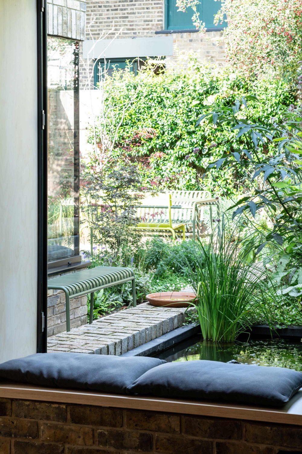 Modern home extension overlooking a landscaped garden with pond and outdoor seating