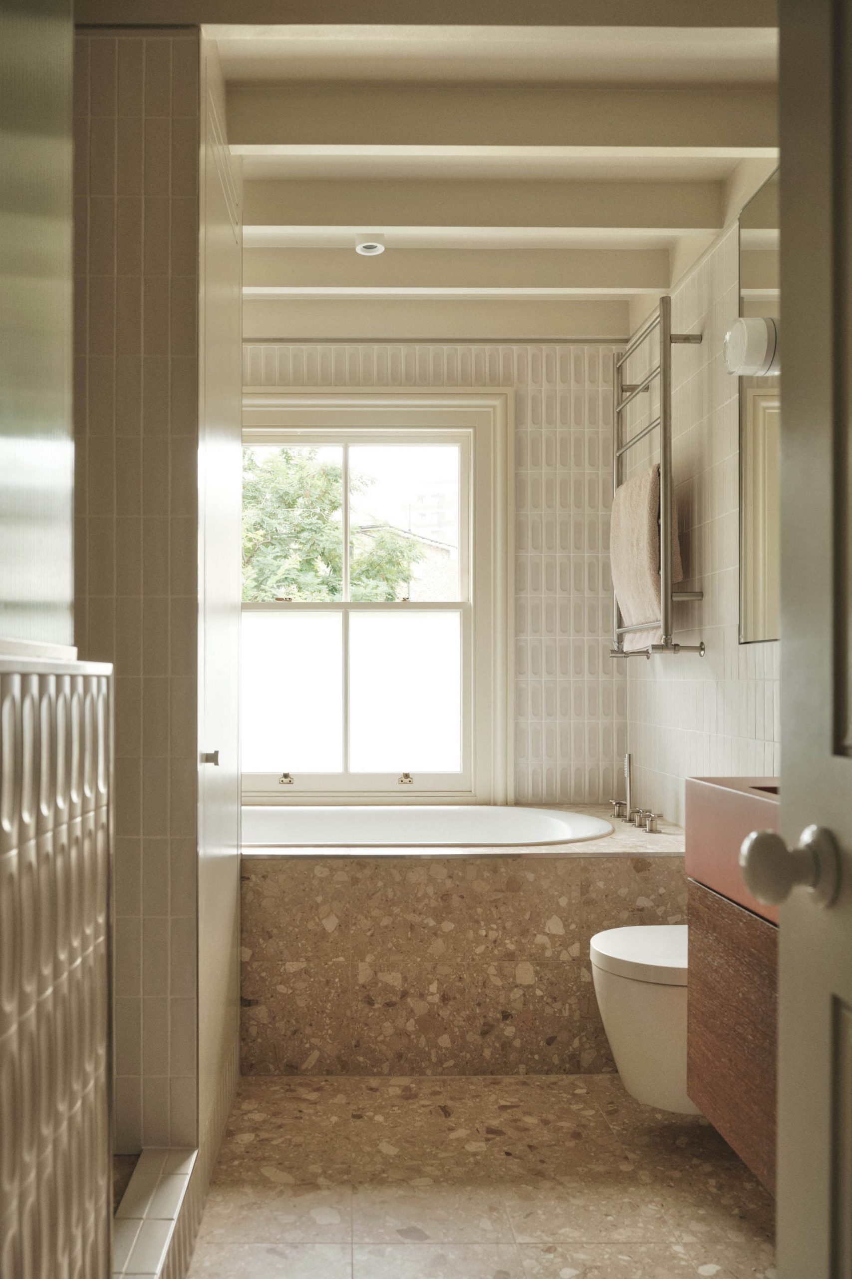 Lauriston bathroom with terrazzo 3D tiles, red concrete sink, oak vanity, built-in bath, exposed joists, and painted ceiling