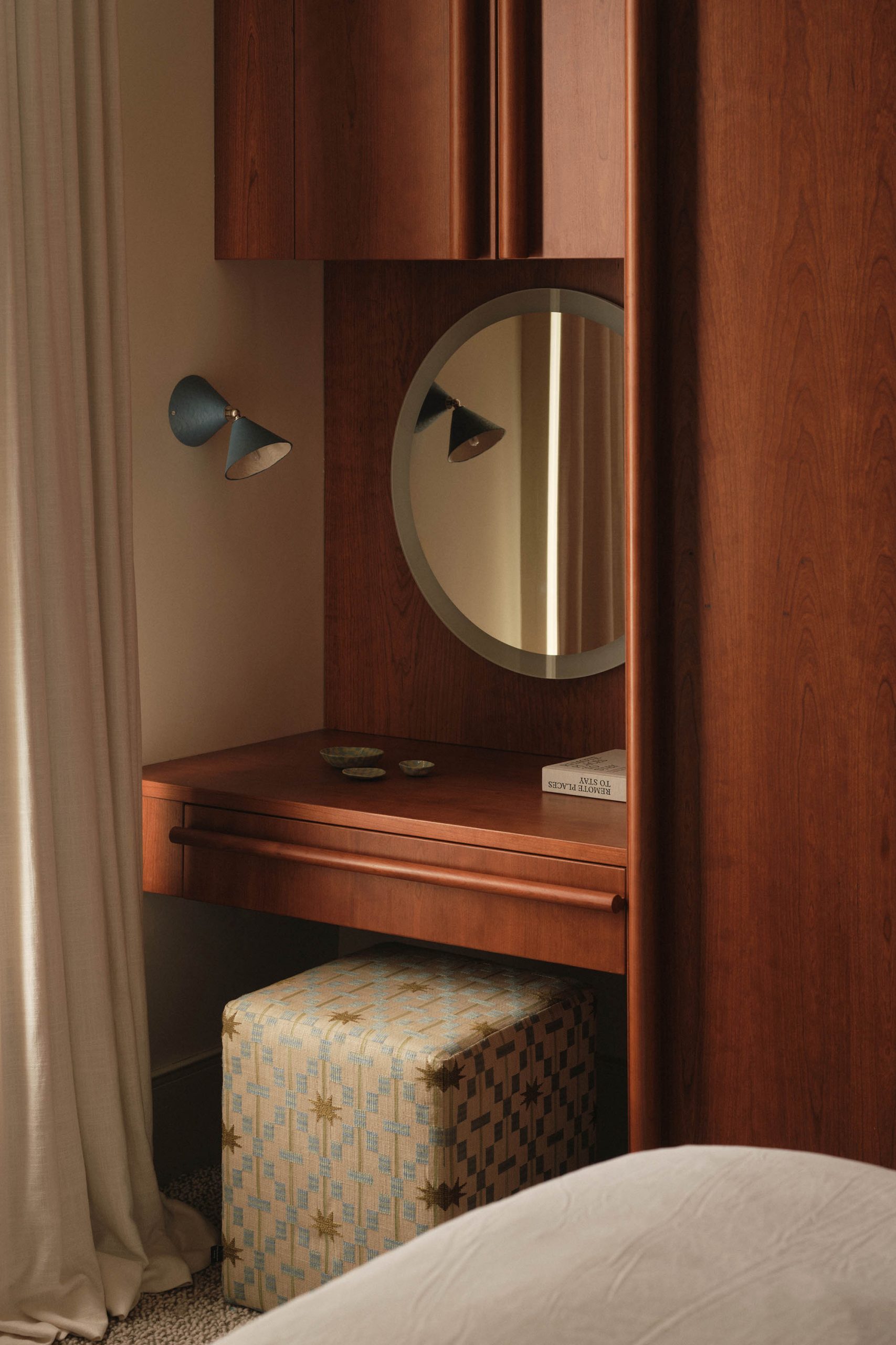 Lauriston bedroom with cherry red stained oak wardrobe, bespoke round handles, built-in vanity, wall light, and ottoman