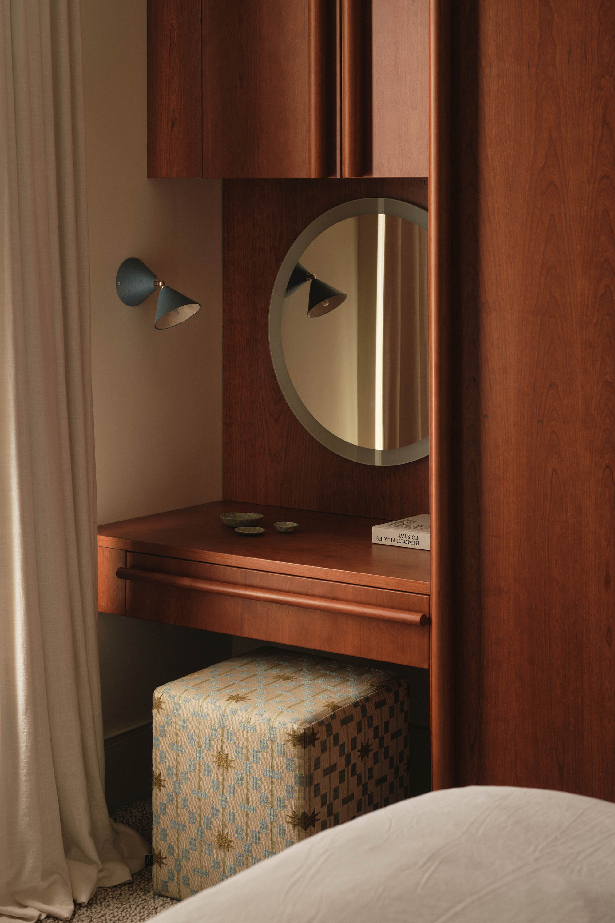 Lauriston bedroom with cherry red stained oak wardrobe, bespoke round handles, built-in vanity, wall light, and ottoman