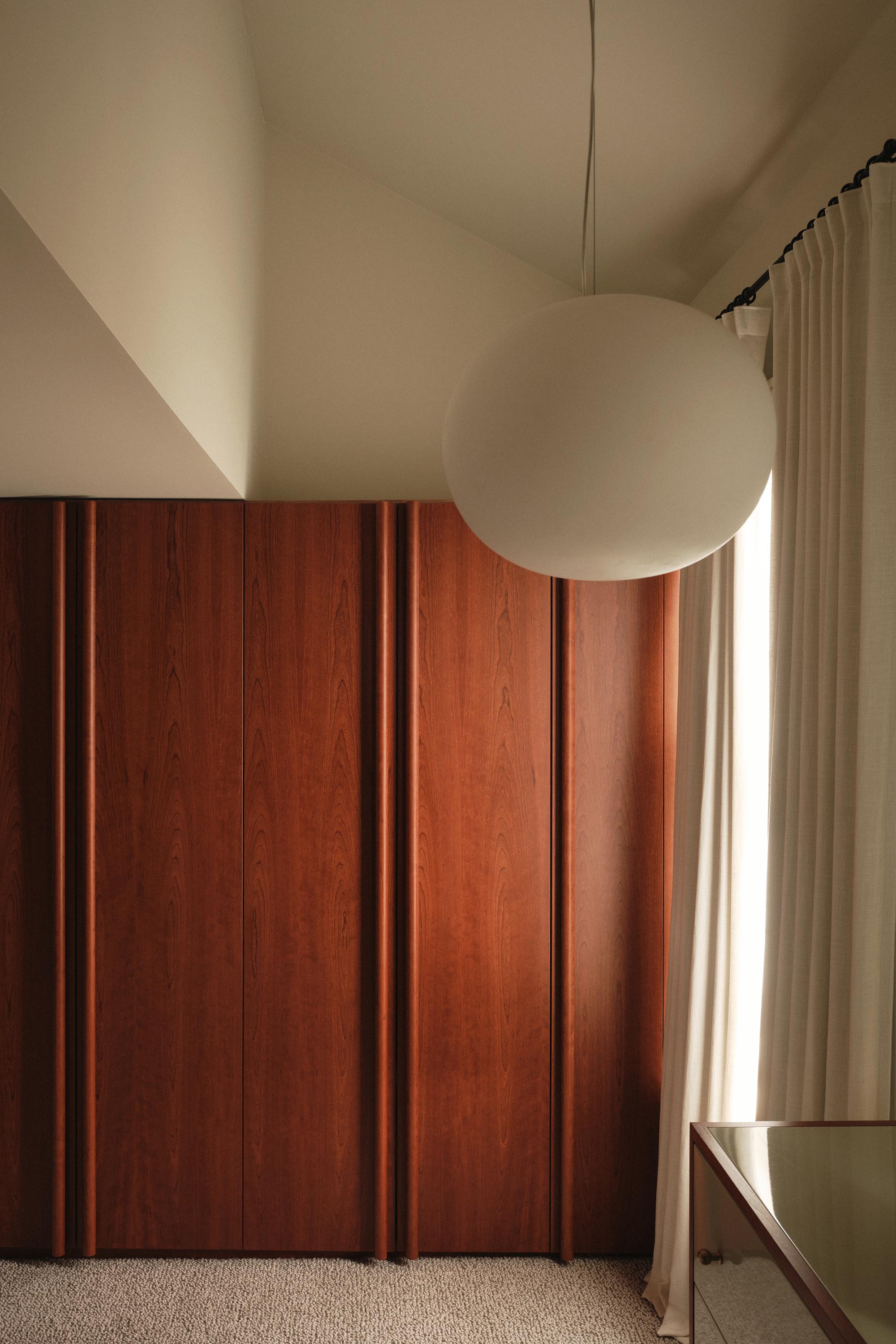 Lauriston bedroom with cherry red stained oak wardrobe, bespoke round handles, double-height space, and pendant globe light