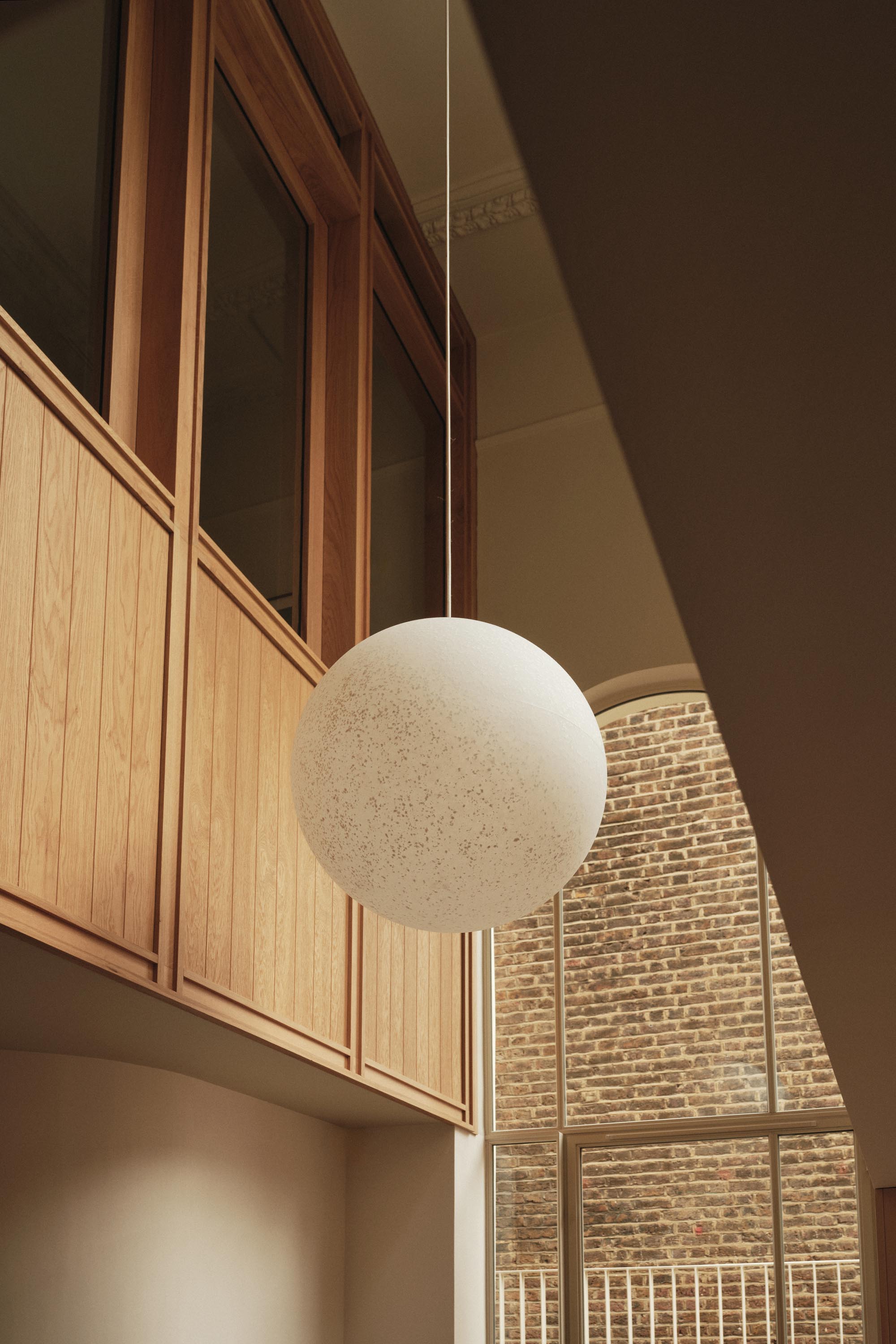 Lauriston double-height space with large globe pendant light, recycled plastic Crittall door, and oak panelling