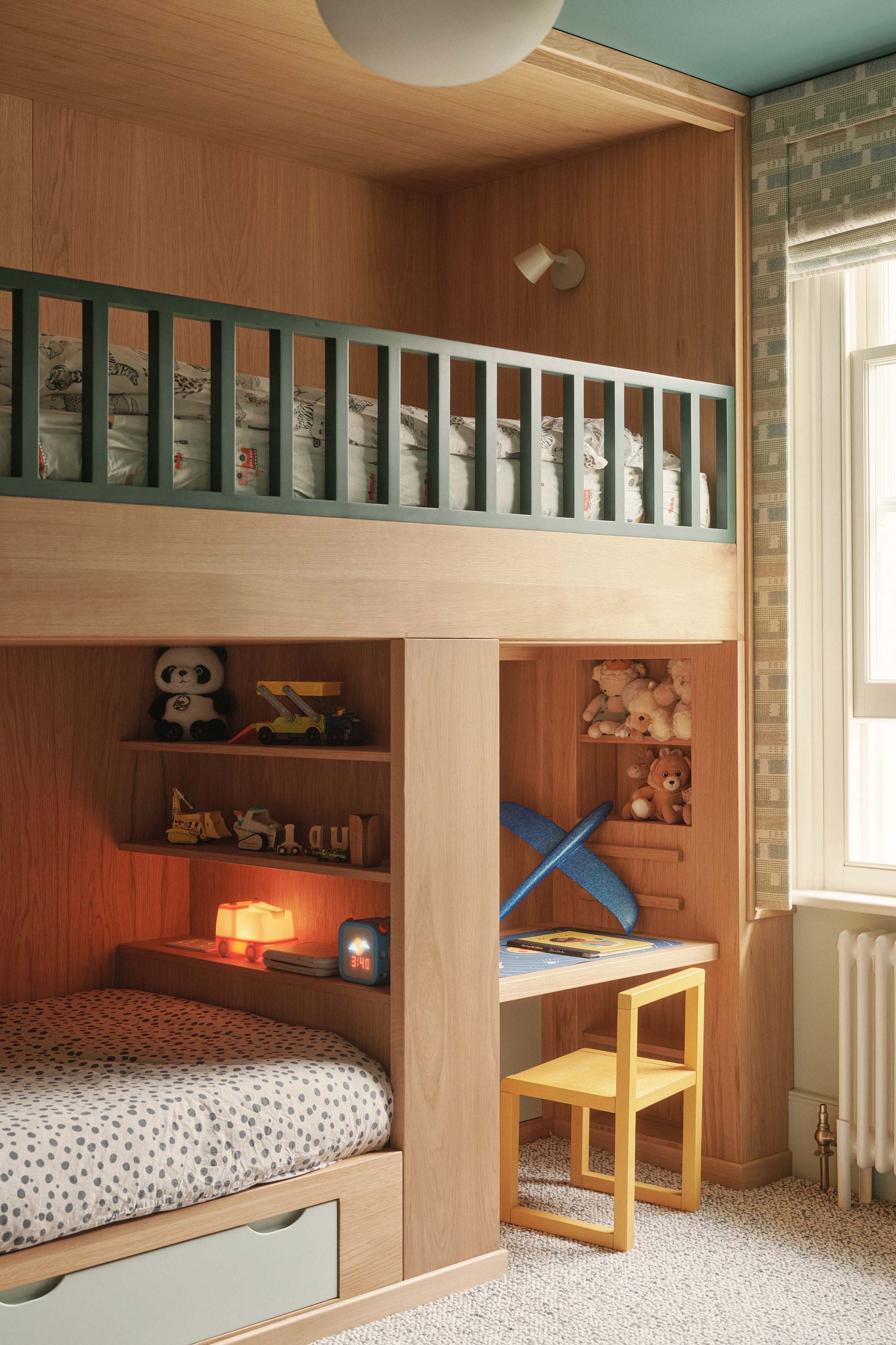 Lauriston kids’ playroom with built-in oak bunk bed, green bespoke joinery, built-in desk, and yellow chair.