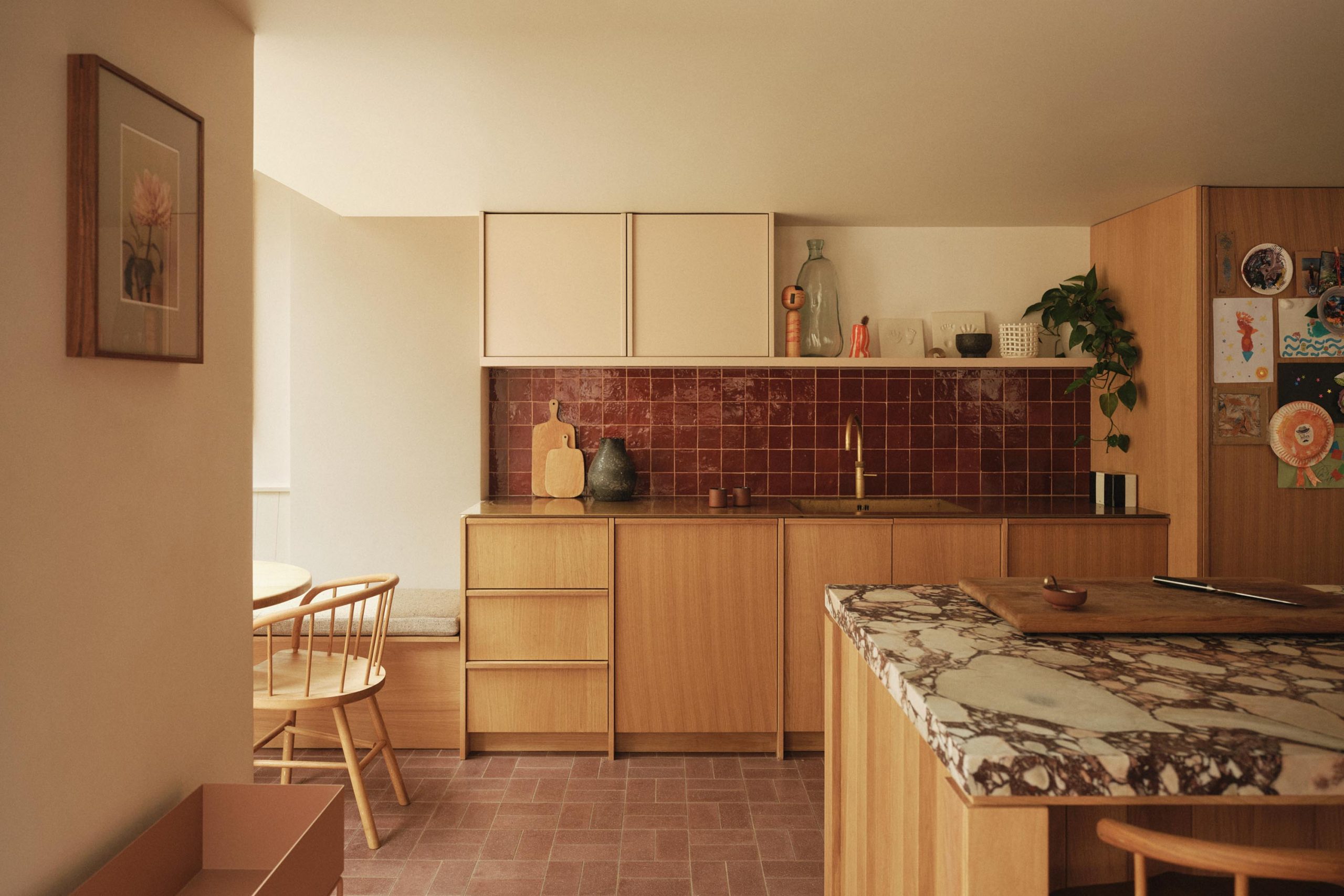 Lauriston kitchen with oak bespoke joinery, central island, marble surfaces, red Zellige tile splashback, and paved flooring.