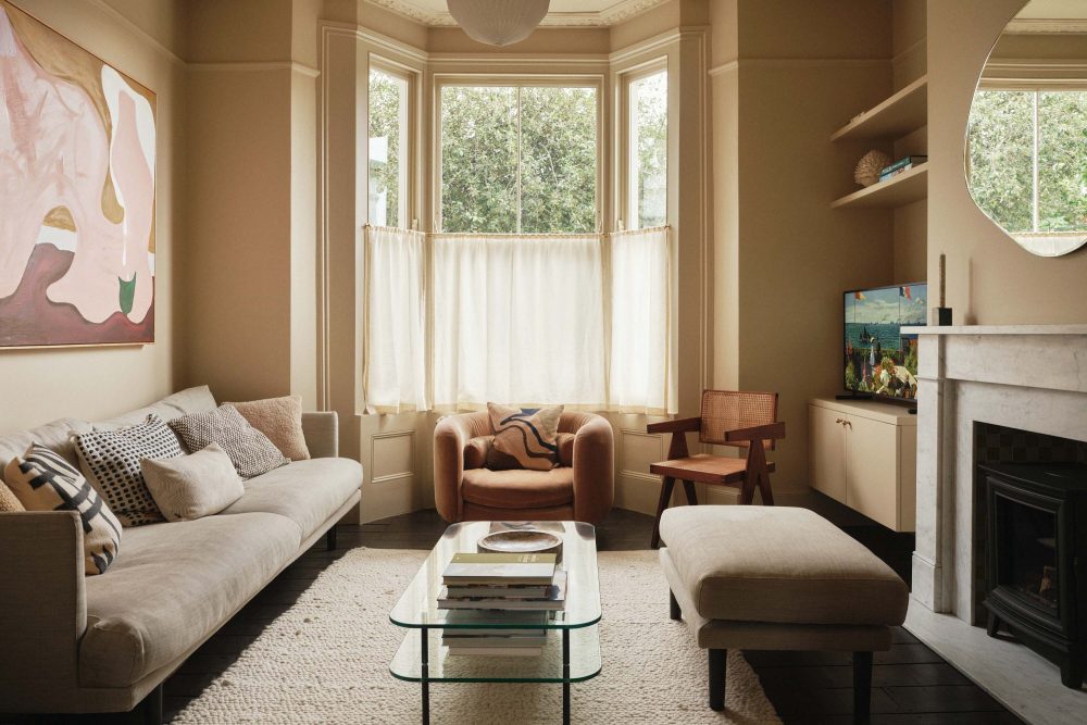 Lauriston snug library with traditional fireplace and woodburner, yellow tiles, coving, modern-coloured sofa, and warm daylight-filled interior