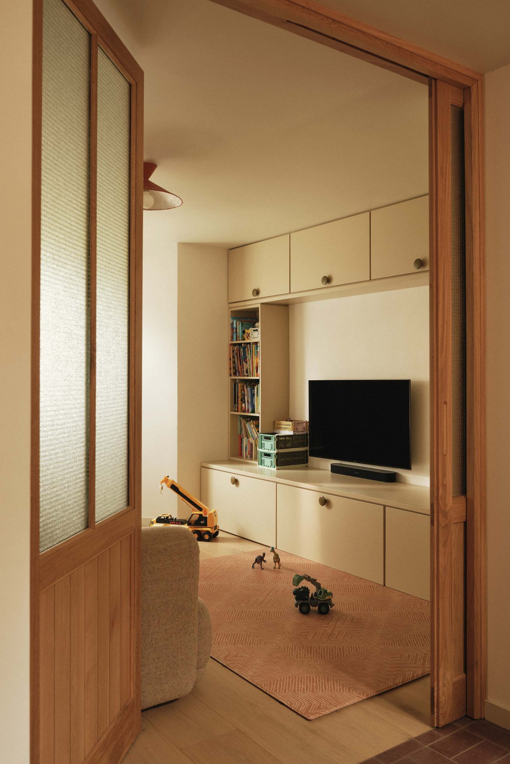 Lauriston snug play area with kids’ toys, warm oak finishes, pocket door, and TV storage joinery