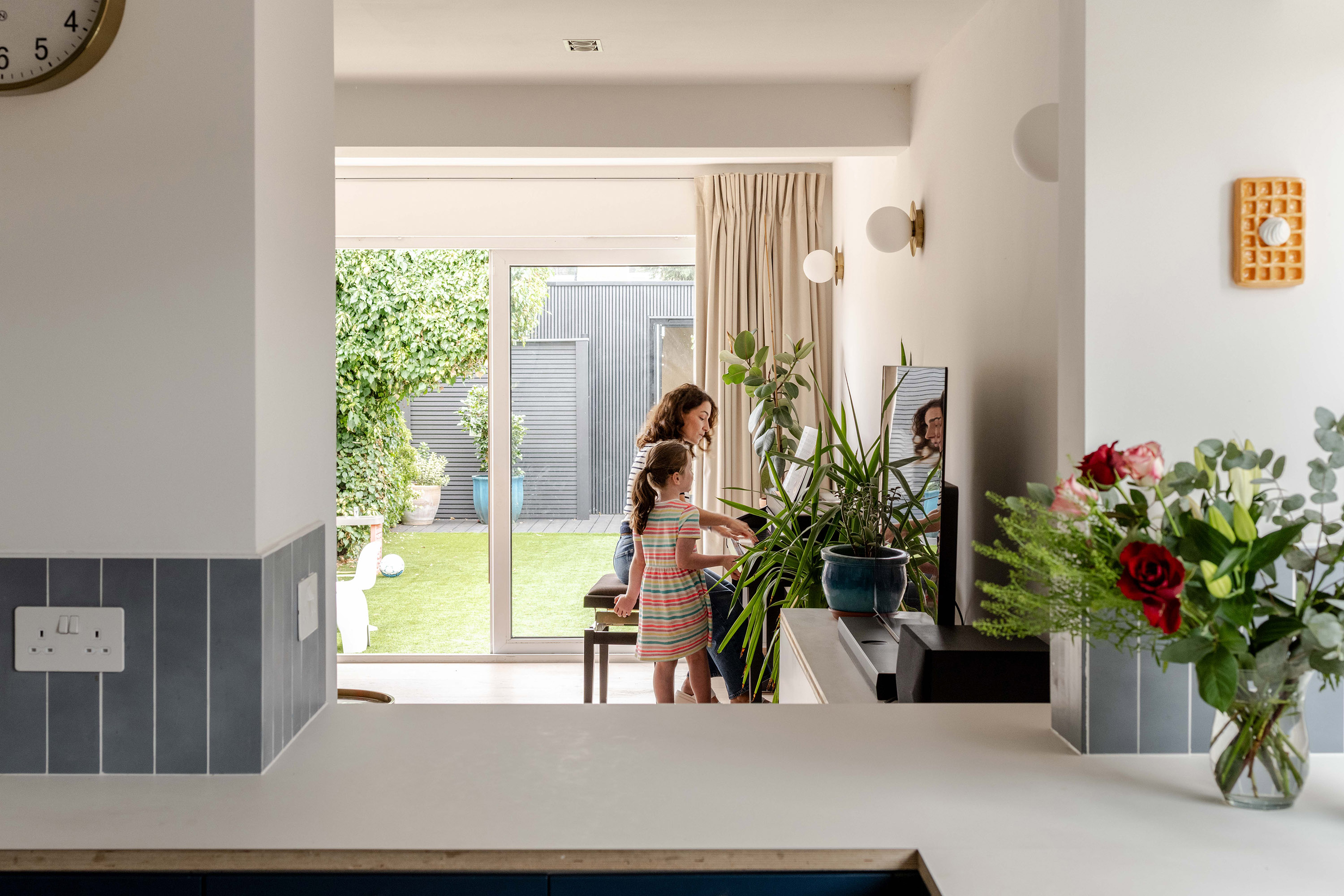 Living space with piano visible, connected visually to the kitchen.