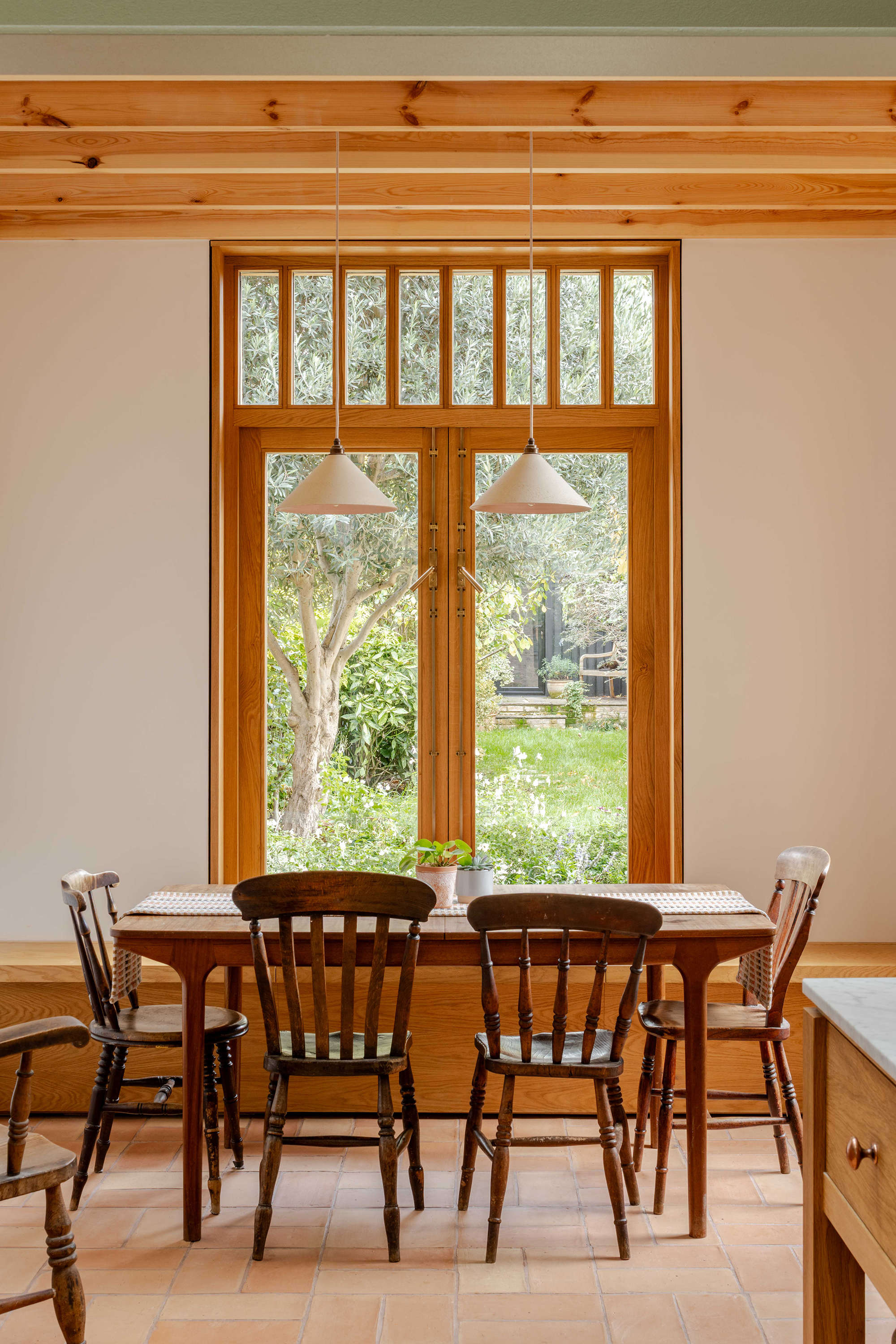 Family dining space in a Stoke Newington rear extension by Bradley Van Der Straeten Architects with terracotta flooring and views to the garden.