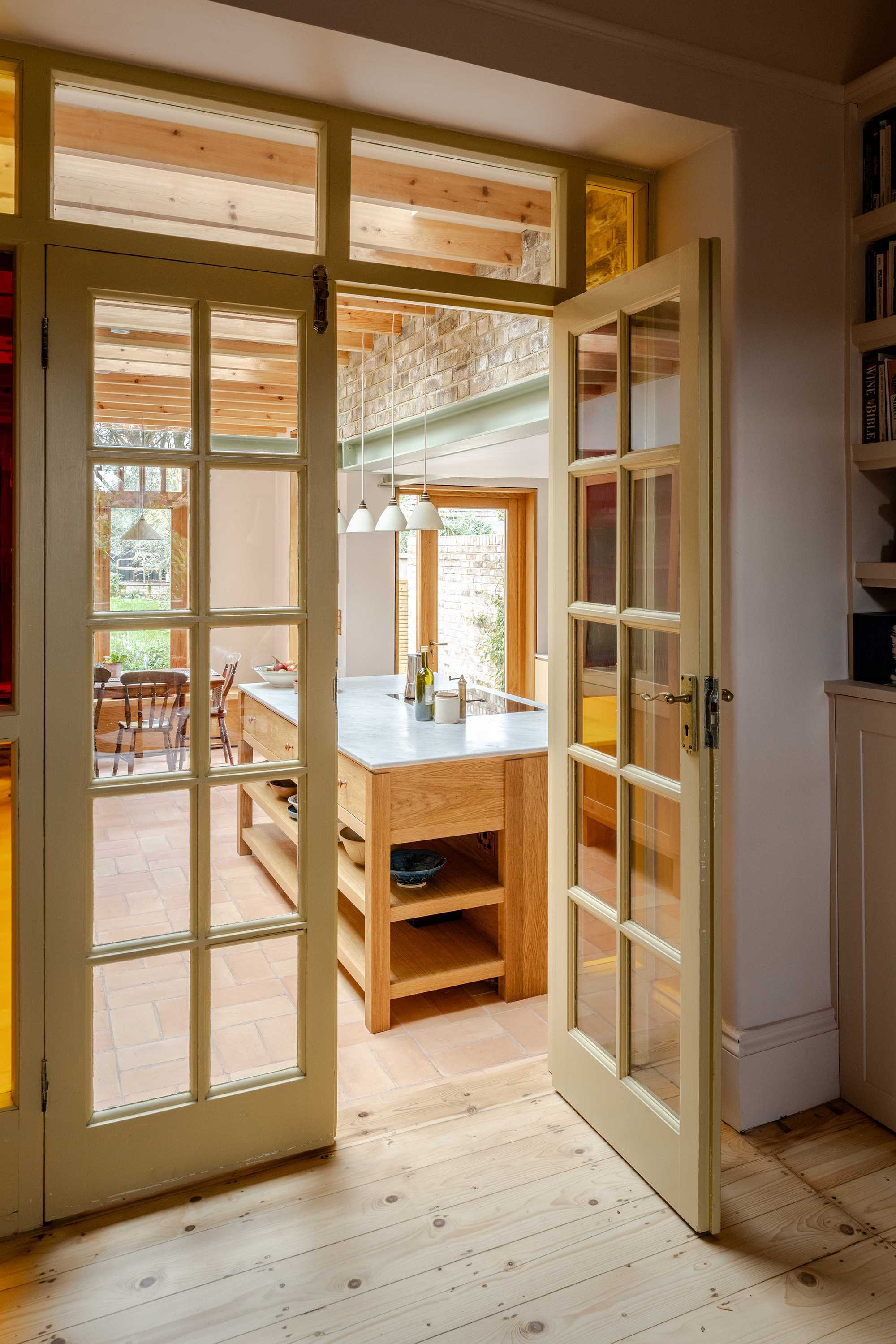 Kitchen and dining space within a Stoke Newington house extension by Bradley Van Der Straeten Architects featuring warm materials and garden views.