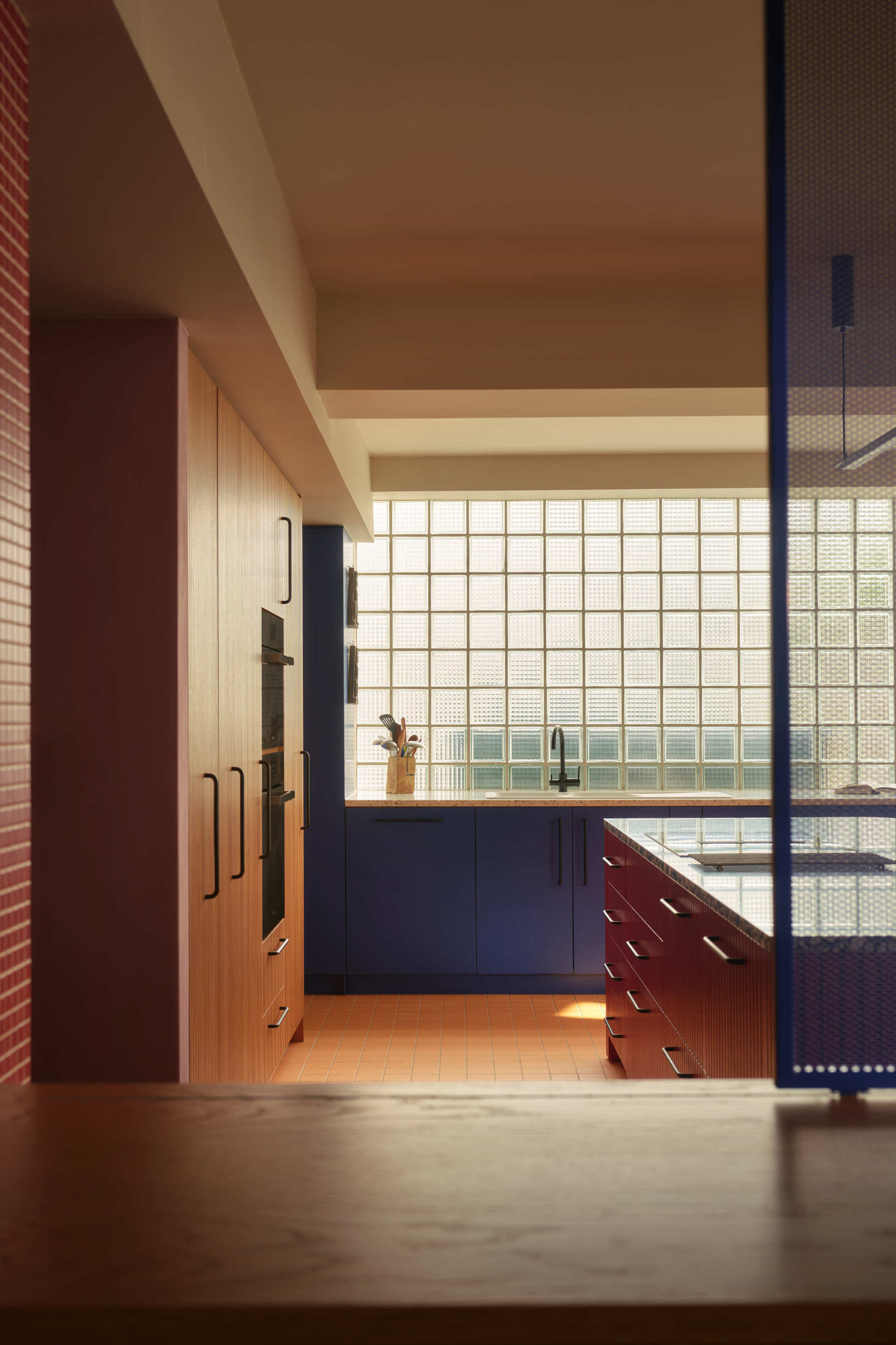 Modern kitchen extension with brick facade and gridded glass wall flooding open plan living space with natural light.