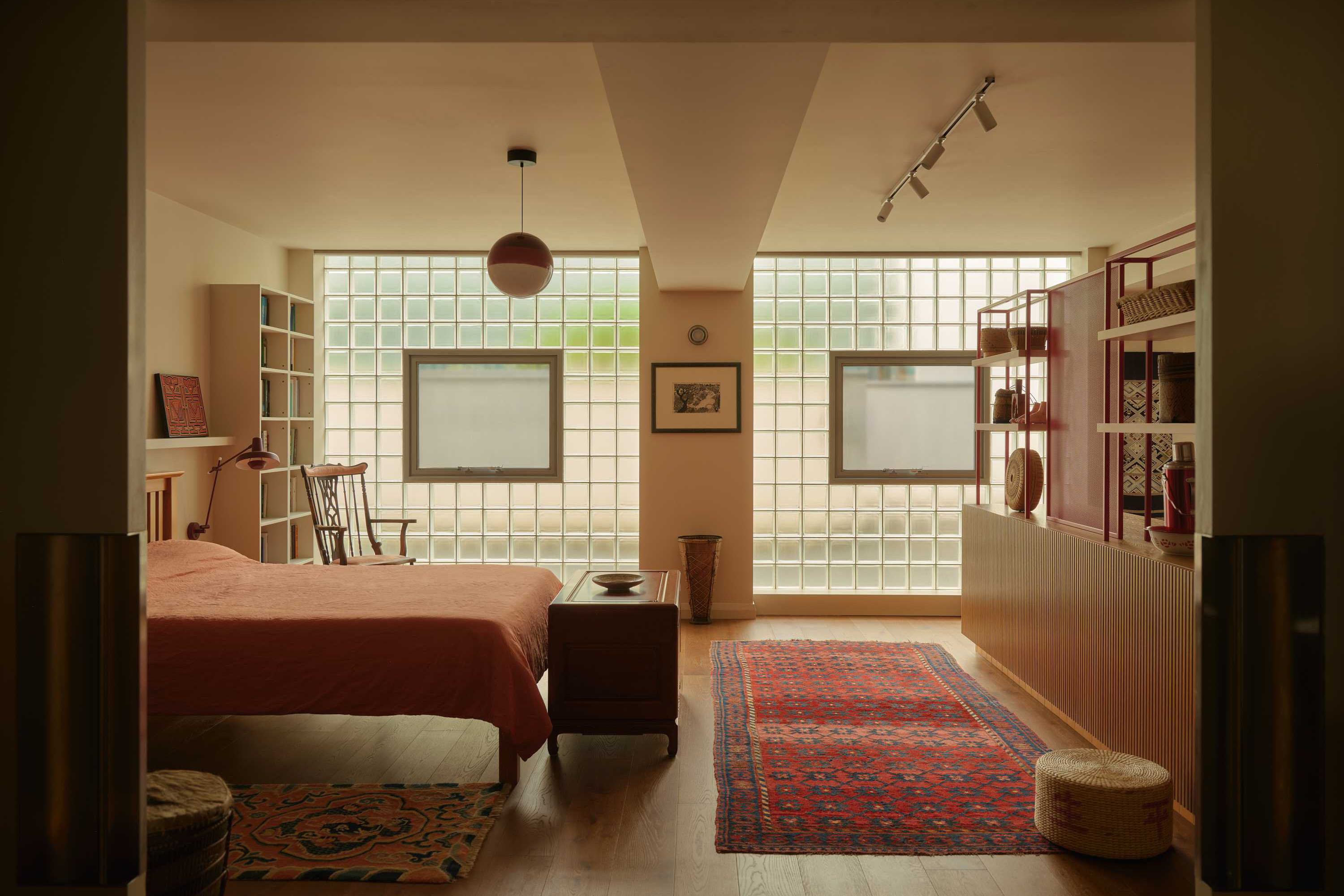 Loft conversion with timber finishes and glass block walls creating bright open plan bedroom space.