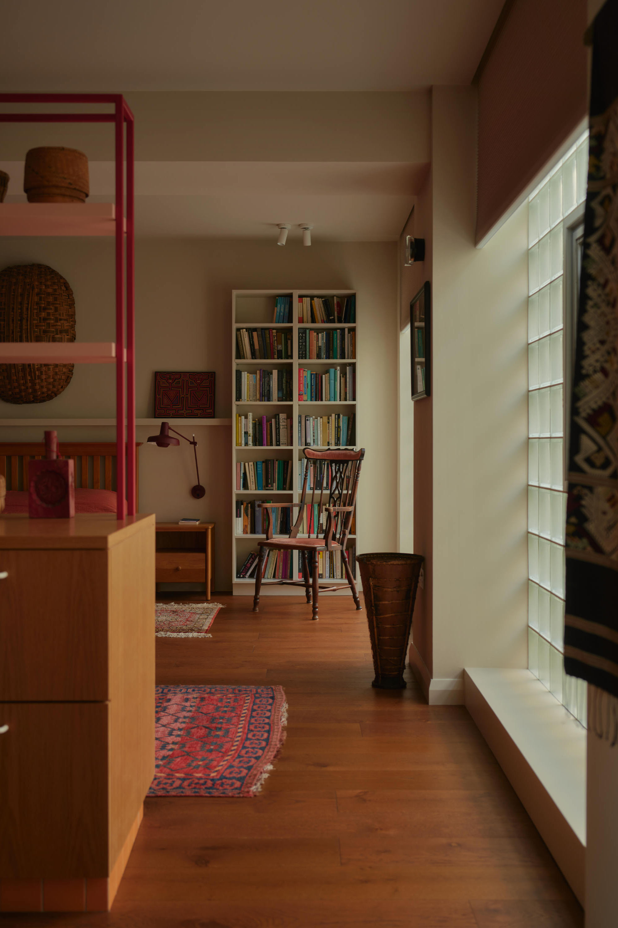 Open plan library corridor with timber flooring, white glazed room divider and built-in bookshelves.