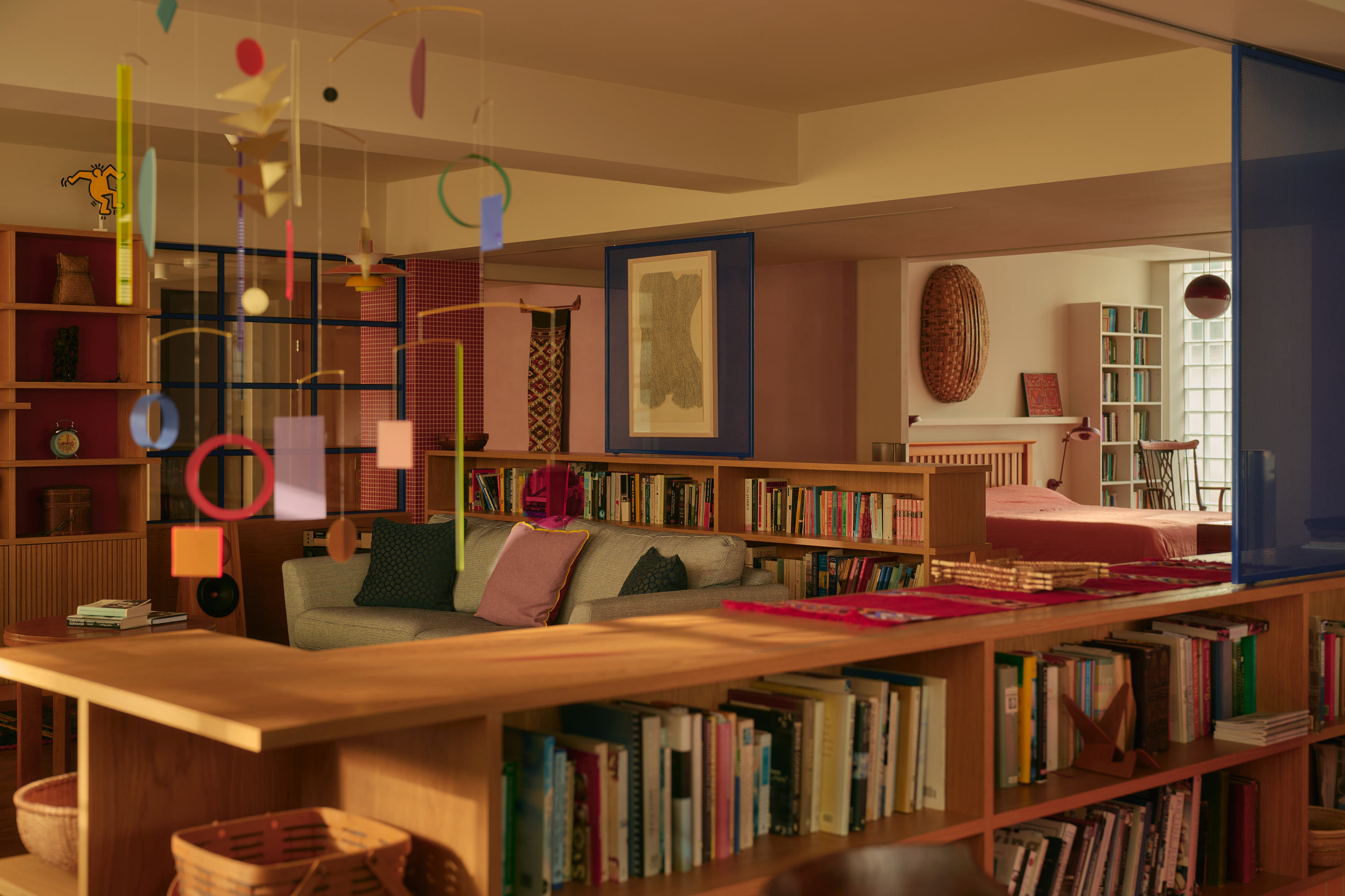 Open-plan loft conversion with timber shelving, glass partition, and warm lighting creating flexible living space.