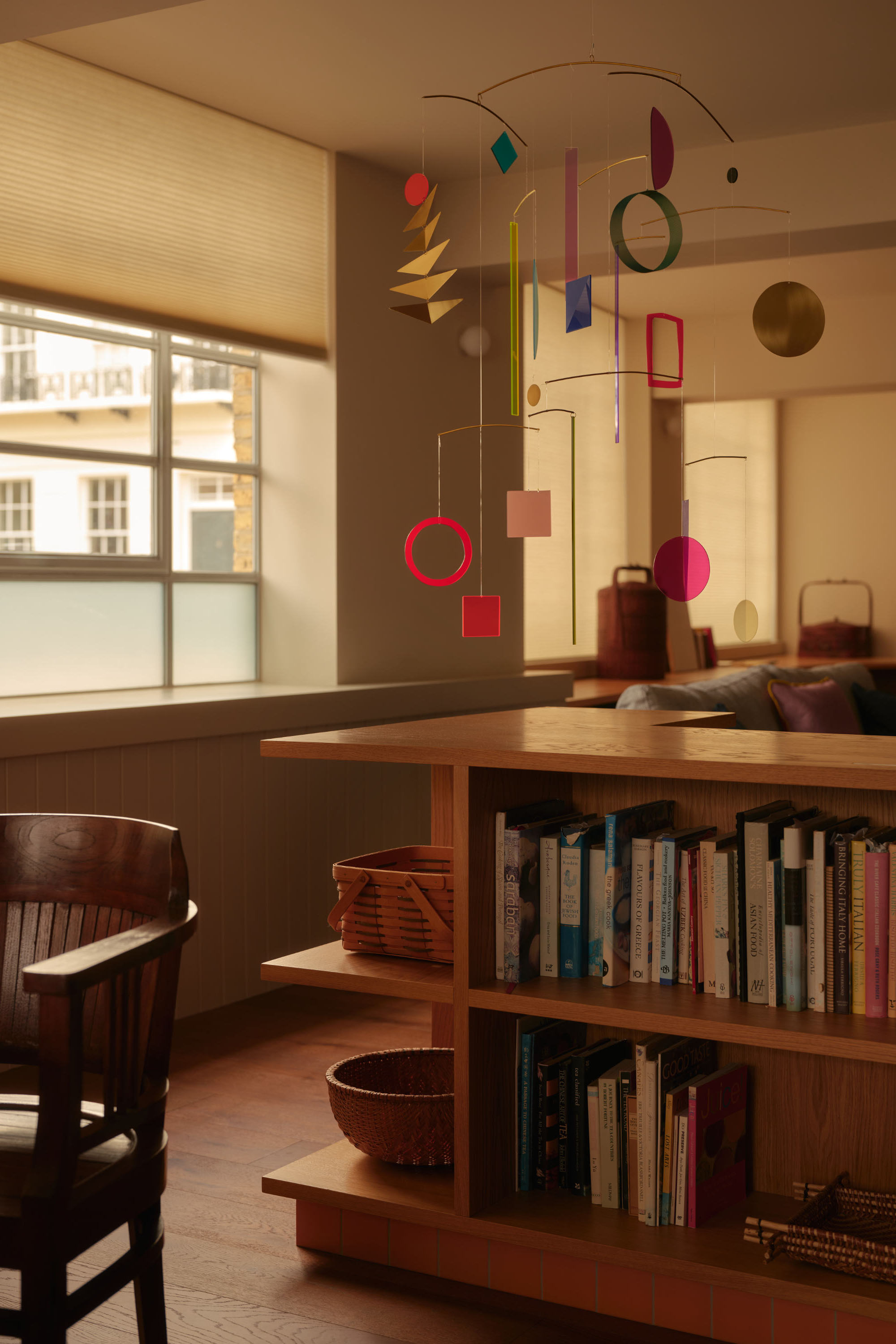 Open plan study with timber built-in shelving and window seat overlooking period building. Natural light.