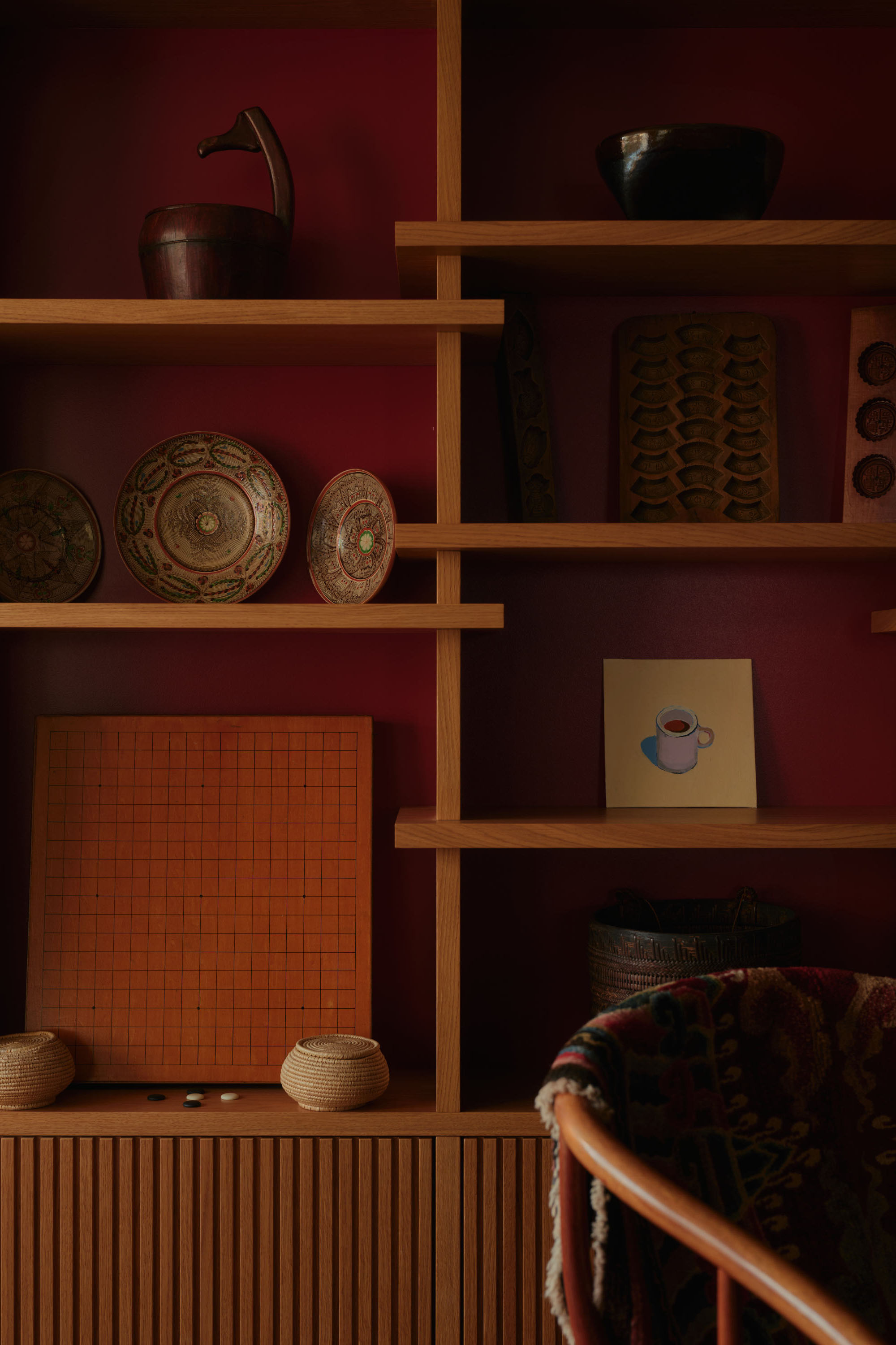 Timber shelving unit against burgundy wall with open plan display space. Modern house extension design.