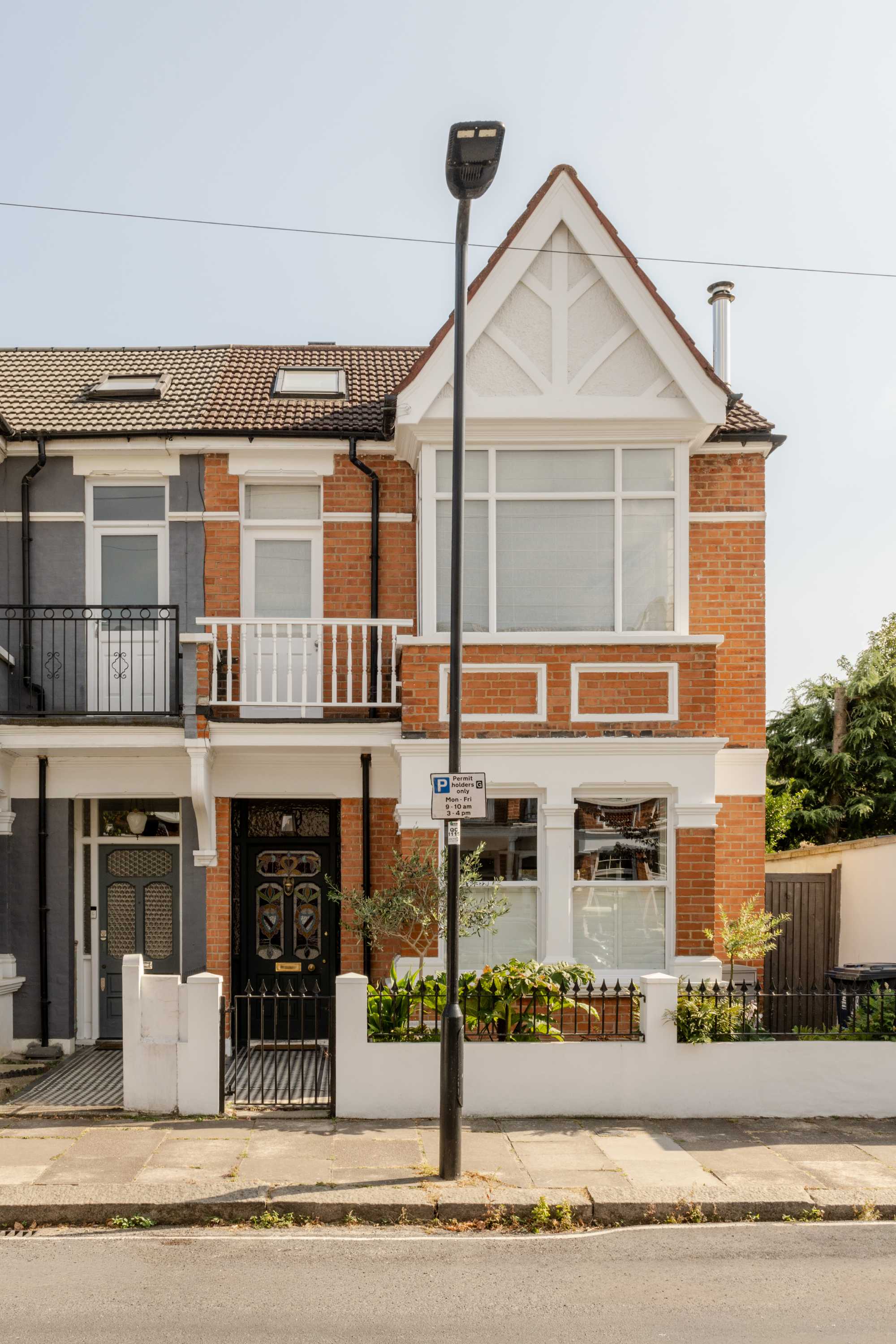 Red brick Victorian townhouse with cream gable extension featuring large glazing.