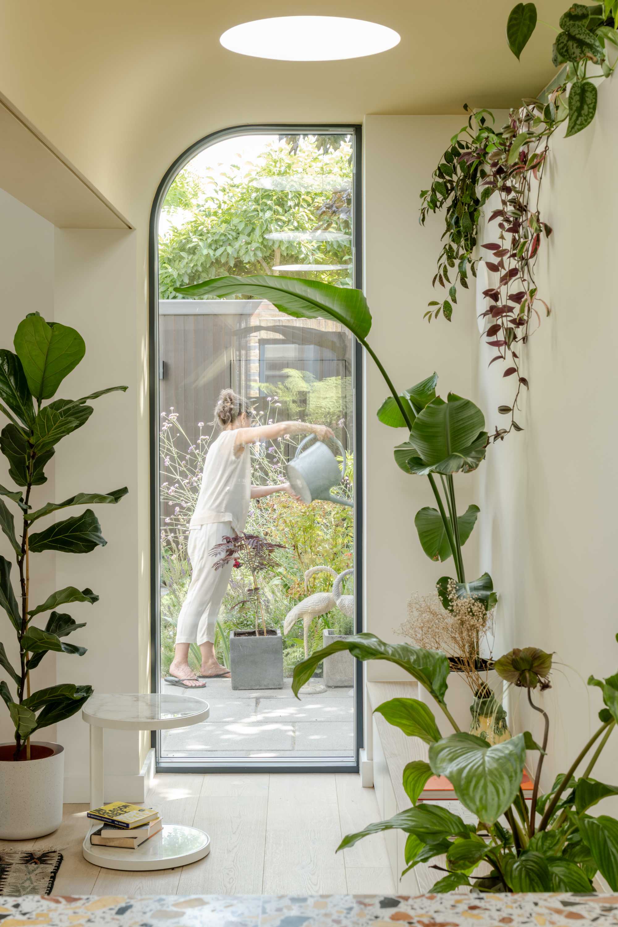 Garden room extension with curved glass door and skylight creates bright open plan living space connecting to garden.