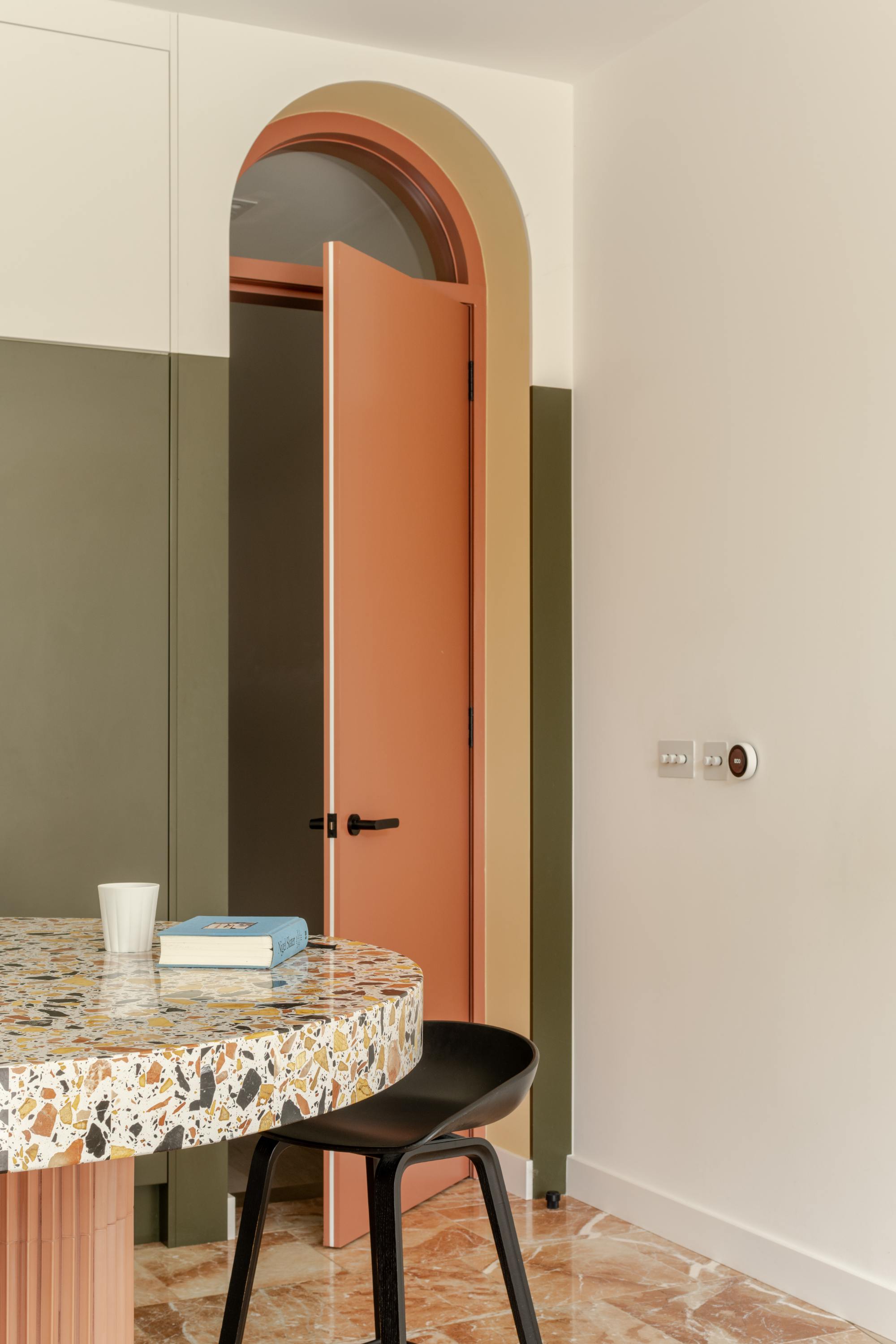 Kitchen nook with terrazzo countertop and arched doorway in open plan living space.