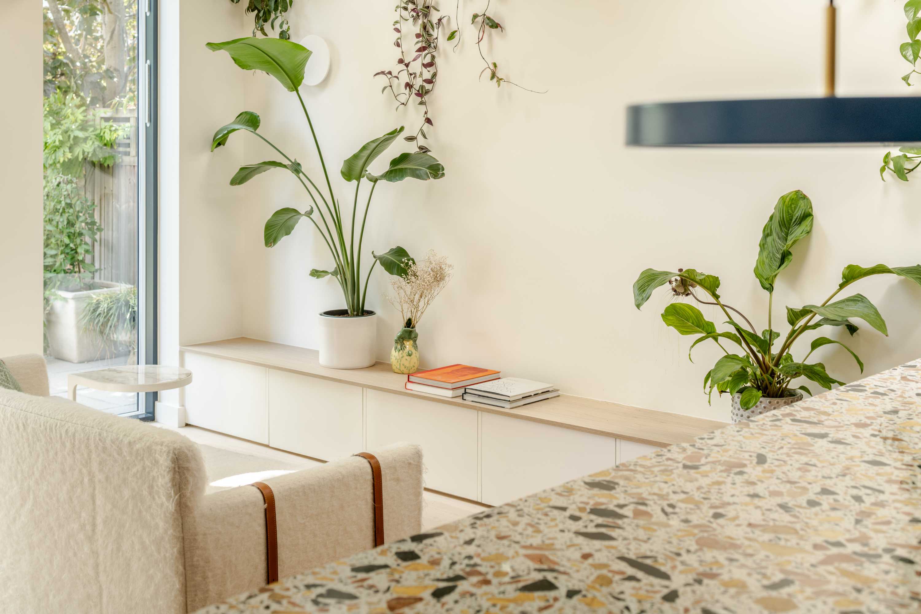 Modern kitchen extension with terrazzo counter top, cream cabinetry, and glass doors opening to garden.