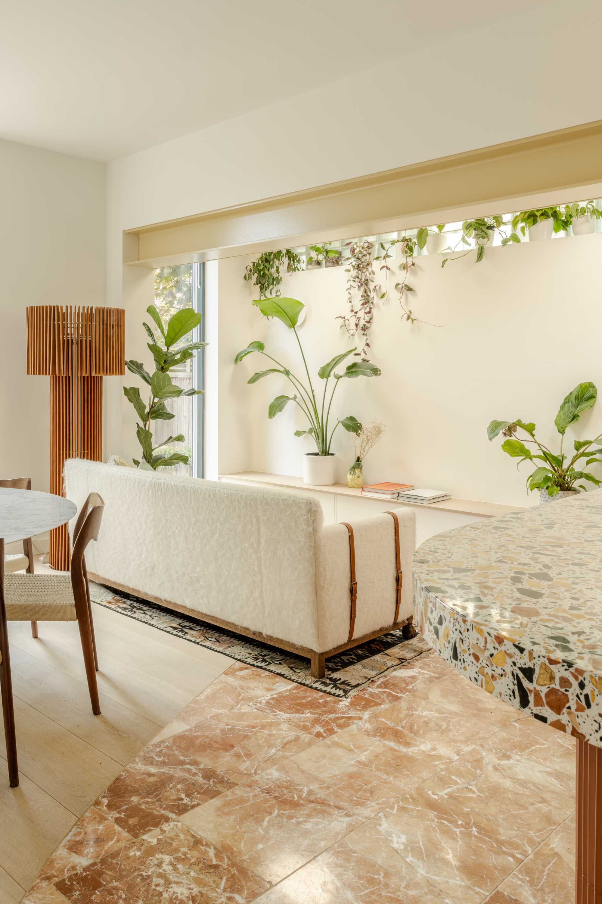 Open plan kitchen extension with terrazzo flooring, large windows, and integrated planting shelf. Modern house extension design.