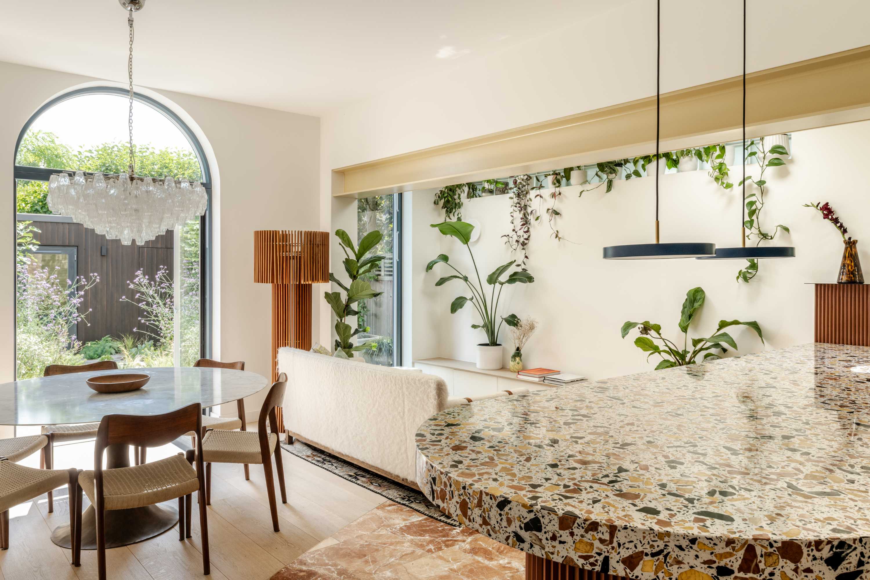 Open-plan kitchen extension with terrazzo counters, glass sliding doors, and garden views. Modern house extension design.
