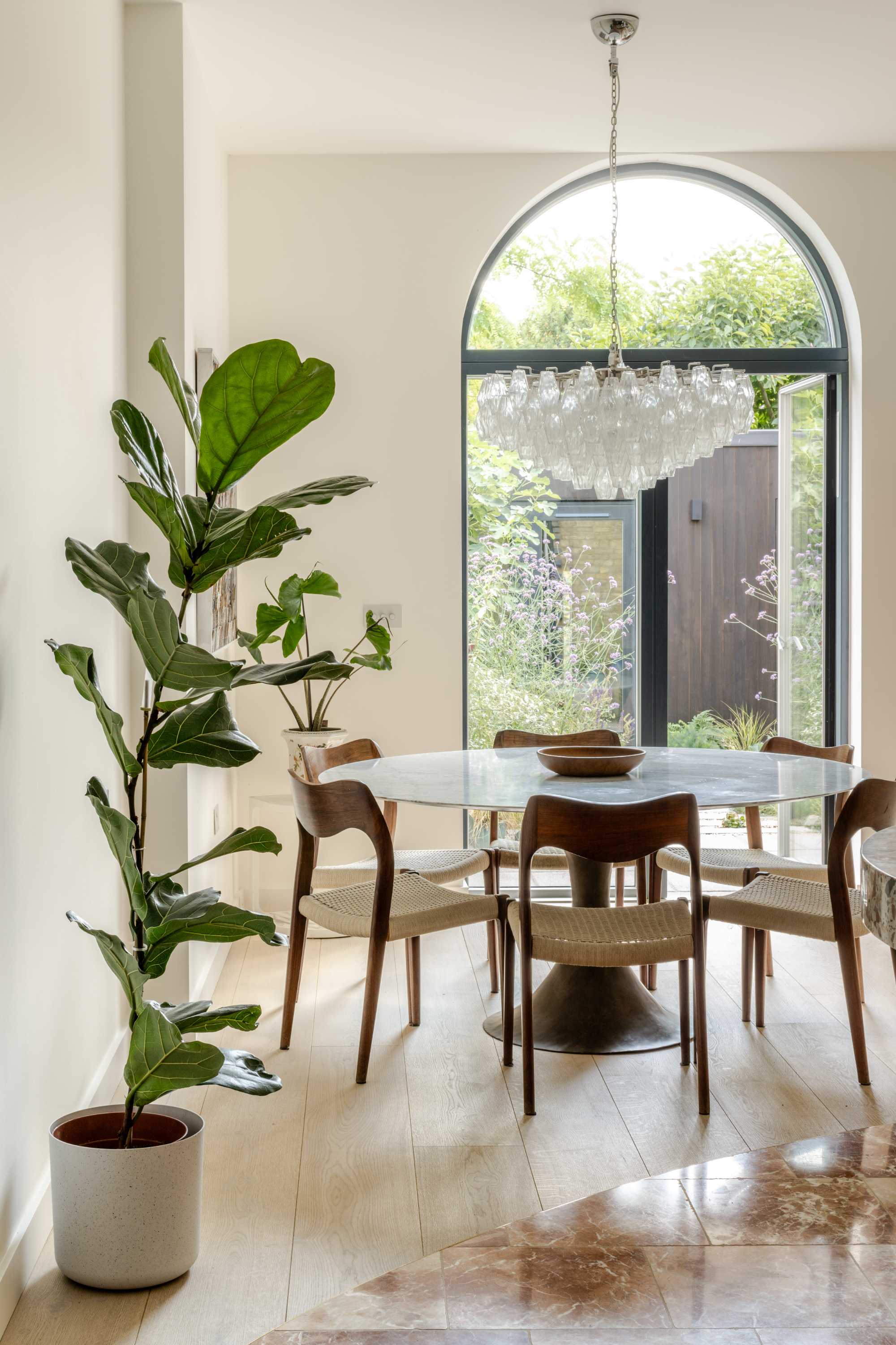 Modern rear extension with arched glass doors, marble dining table, and open plan living space flooded with natural light.