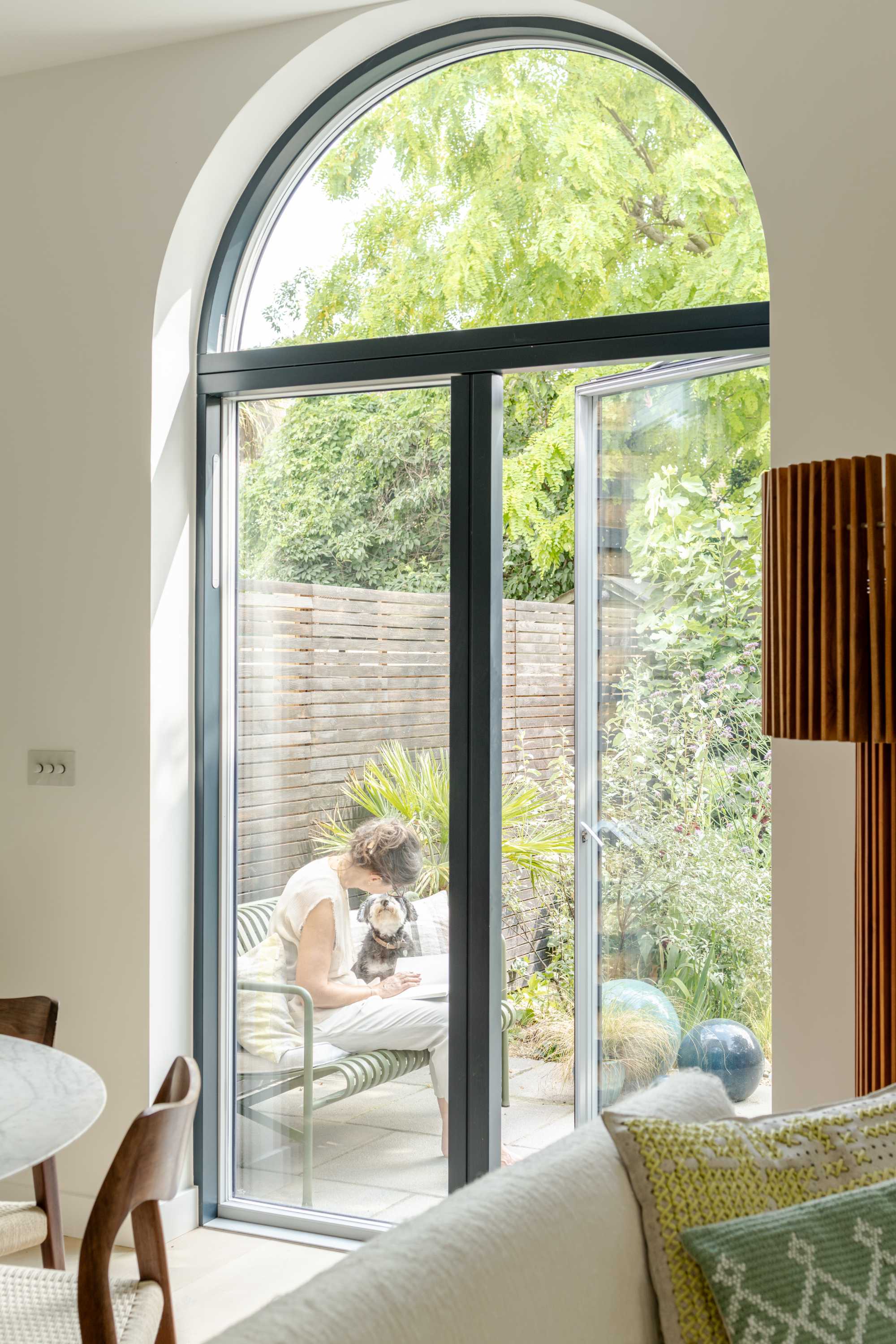 Modern rear extension with black-framed glass doors and circular window opening to garden.