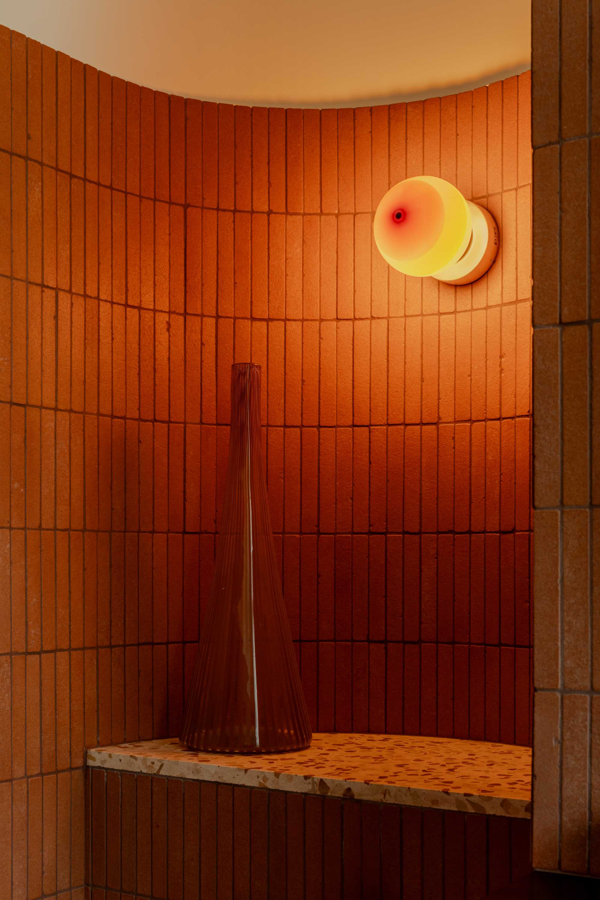 Curved bathroom interior with terracotta tiles and globe lamp. Modern bathroom design.