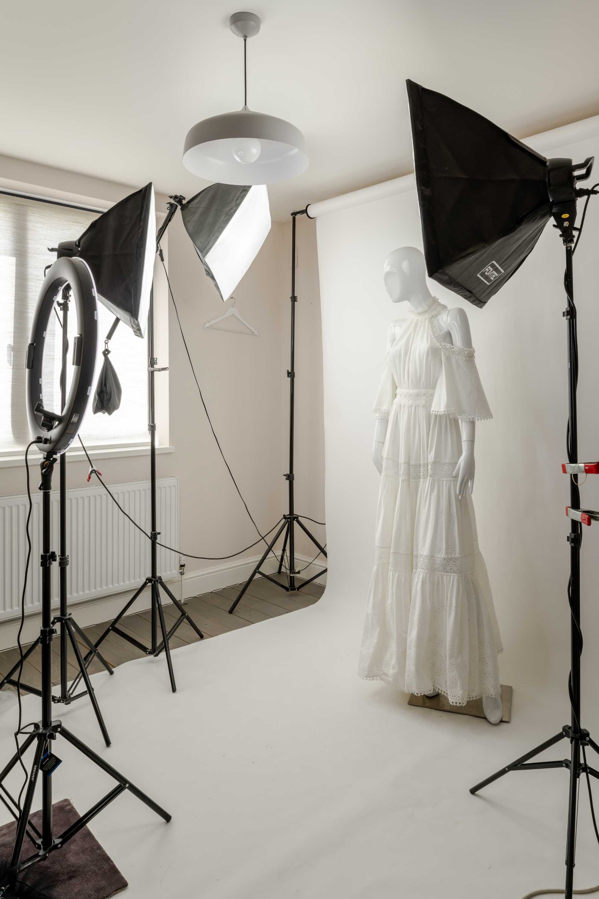 Minimalist photography studio with white walls, polished concrete flooring, and professional lighting setup for fashion shoot.